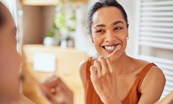 Woman smiling while brushing her teeth