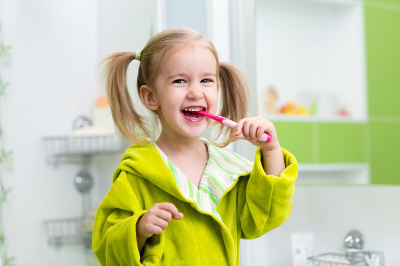 little girl smiling brushing her teeth