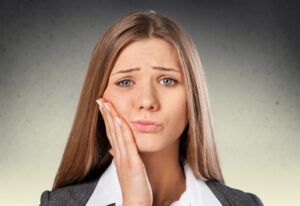 Woman with hand on her face experiencing jaw pain 